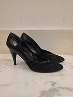 Full side view of both black leather high-heel pumps