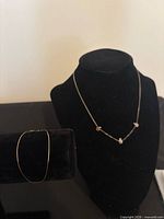 Gold bracelet on display form beside silver necklace on bust