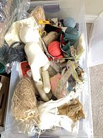 Overview of tote showing yarn, doll form, rotary cutter, raffia, fabric, serger cones and assorted notions