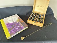 Overall view of book, open box of oils and necklace