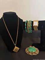 Full view of necklace, watch, bracelet and brooch on stands