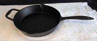 Top view of Lagostina cast-iron skillet showing cooking surface, long handle, helper handle and pour spout