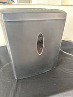 Front view of black Staples paper shredder showing oval viewing window and attached power cord