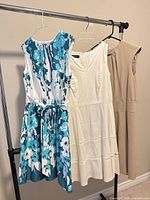 Front view of all three dresses on hanging rack