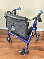 Side view of blue Elite foldable rollator walker showing frame, padded seat, storage pouch, wheels and hand brakes