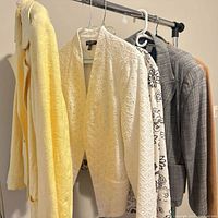 Row of hanging jackets showing yellow, white eyelet, patterned, grey tweed and brown corduroy pieces