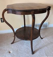 Full view of dark-stained wood accent table showing shaped top, curved legs, and round lower shelf