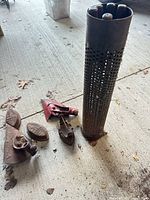 Group shot showing perforated tube and cast iron pieces on concrete