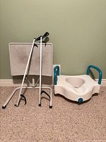 group shot of raised toilet seat, two reachers, folding table