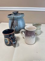Group view of cookie jar with lid and three mugs