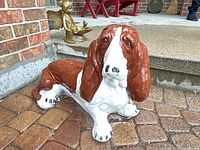 Front angled view of cement basset hound statue showing head and body coloration