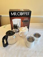 Overall lot showing Mr. Coffee boxed coffee maker, spare carafe, Dansk thermos and two travel mugs