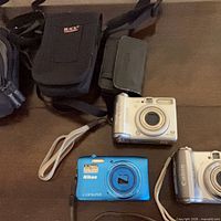 Three digital cameras and three cases laid out