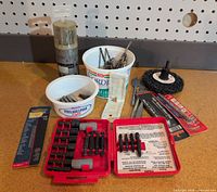 Entire lot displayed: red Craftsman bit case, carded drill bits, loose bits in tubs, abrasive wheel, reciprocating saw blades, plastic tube