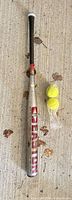 Full view of Easton bat and two tennis balls on concrete surface