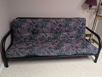 Full view of futon showing metal frame and patterned mattress