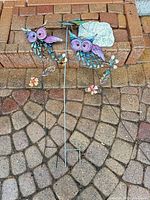 Two owl stakes, plain stake and butterfly plaque on patio
