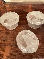 Three covered frosted glass trinket dishes, two floral, one seal lid
