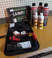 Group shot showing AMPZ jump starter kit box, open accessory case with cables and adapters, three FW1 wax cans, two Scratch Away bottles
