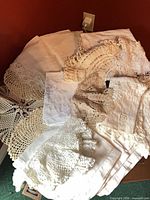 Group of assorted lace linens piled on surface