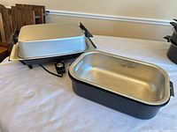 Electric griddle with lid and roaster pan on table