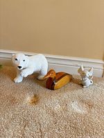 Group shot of polar bear, wooden duck, porcelain mouse on carpet