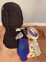 Group shot of massage seat, paraffin pot, BP monitor, wooden massager, water bottle cover, towels