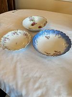 Three of the porcelain bowls on table: blue-rim floral, violet floral, ivory with roses