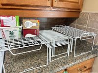 Group of white plastic-coated wire shelves on countertop