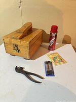Closed wooden box, aerosol can, laces pack, plier
