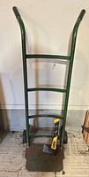 Full view of green hand truck with hatchet resting on footplate