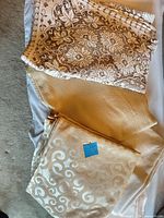 Three folded tablecloths: beige lace, cream waffle-weave, cream swirl jacquard