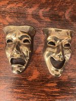 Front view of both brass comedy and tragedy masks