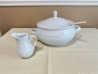 Tureen with lid, ladle, and cream pitcher grouped on table