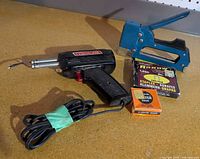 Staple gun, soldering iron, cords, staples box, solder box overall view