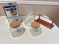 Group view of stainless canisters, three glass jars and wooden napkin holder