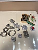 Overall lot: cookie press components in box, twelve assorted aluminium cookie cutters laid out