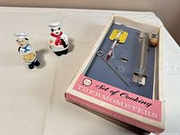 overview of boxed thermometers and two ceramic chef pieces