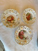 All three reticulated porcelain plates showing fruit and floral motifs