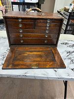 Front view of closed oak machinist chest showing drawers and drop panel