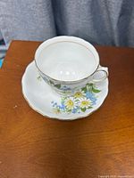 Teacup on saucer showing floral design and gold trim