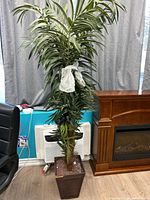 Full view of tall artificial palm tree in brown planter
