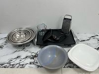 Group shot of all items including grill, bowls, ceramic pieces, grater, measuring cup, electric tool