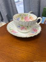 Teacup sitting on saucer displaying floral pattern and gold rim