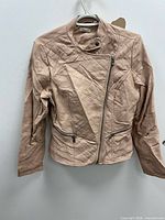 Full front view of blush pink faux leather moto jacket on hanger