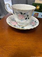 Teacup on saucer showing floral pattern and gold rim