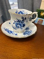 Teacup on saucer, showing blue floral pattern and gold rim