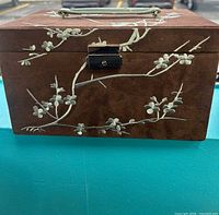 Front view of brown suede jewelry box with floral embroidery and latch
