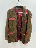Front view of brown suede fringe jacket with red trim and beadwork