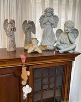 Group of angel figurines on cabinet top showing size relation and condition